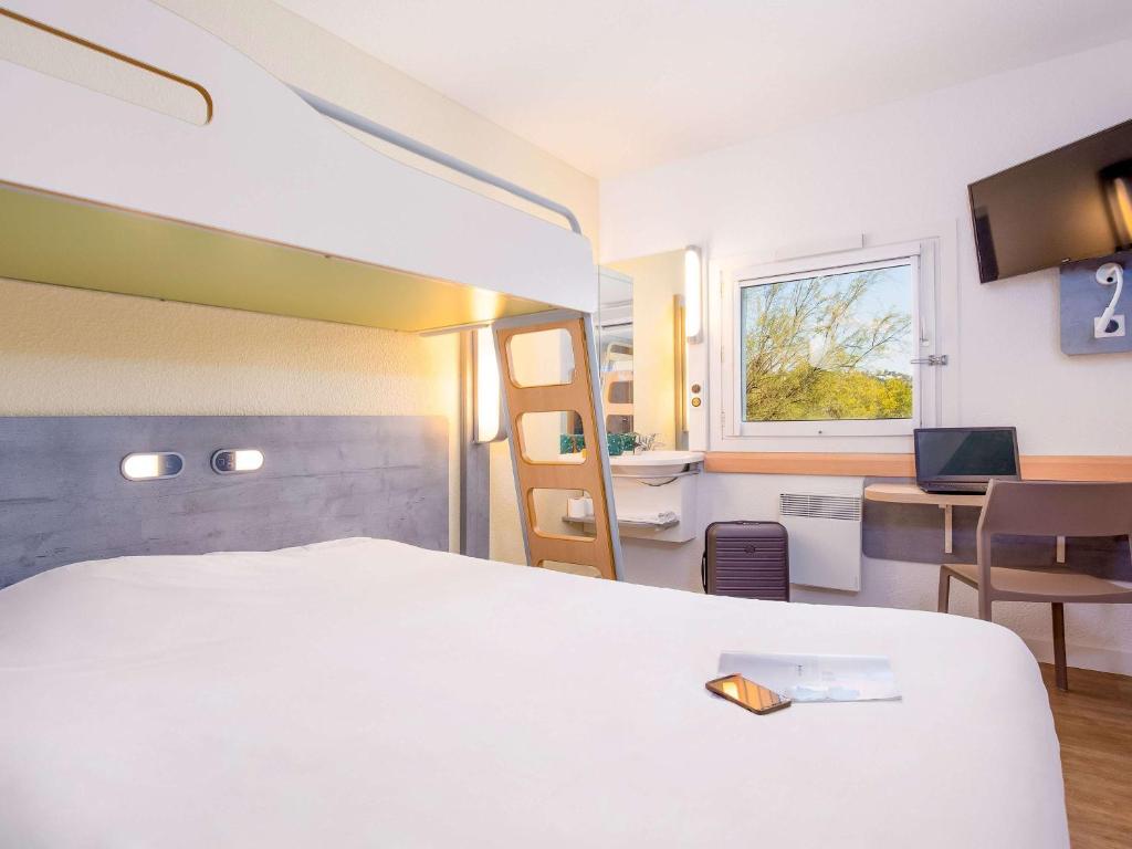 Cette chambre comprend un lit blanc et un bureau. dans l'établissement Ibis Budget Fréjus Capitou, à Fréjus