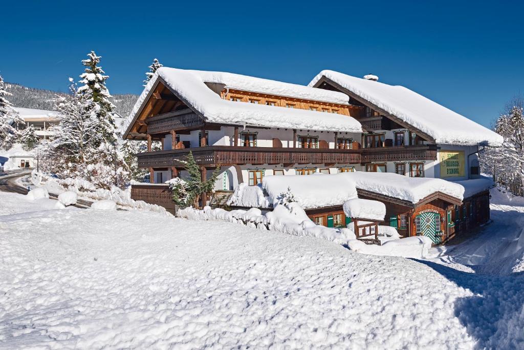 una casa cubierta de nieve delante en Biohotel Walserstuba, en Riezlern