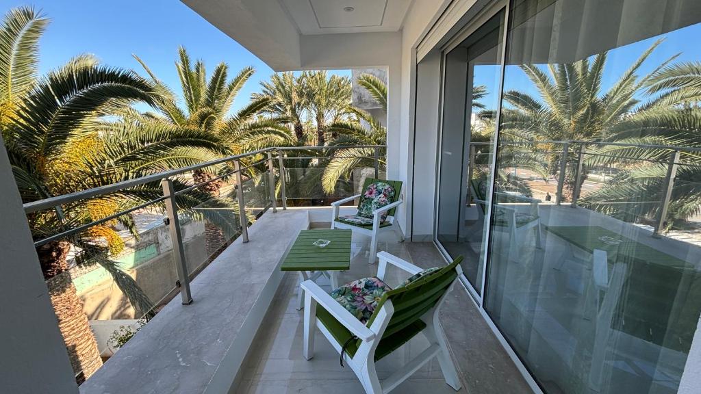 einen Balkon mit einem Tisch, Stühlen und Palmen in der Unterkunft Appartement Port El Kantaoui, Kanta Sousse in Sousse