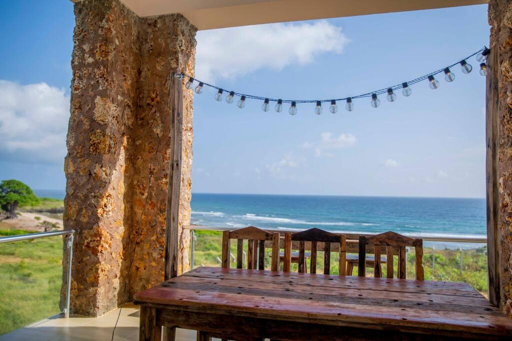 a wooden table with two chairs and a view of the ocean at Kumekucha Ocean View in Dar es Salaam