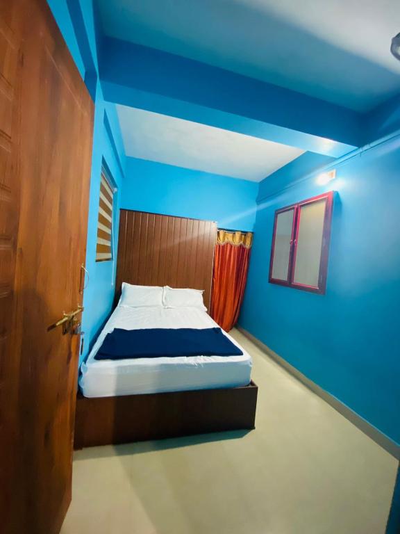 a bedroom with a bed with blue walls and a door at VEE CEE TOWER FURNISHED APPARTMENT in Sultan Bathery