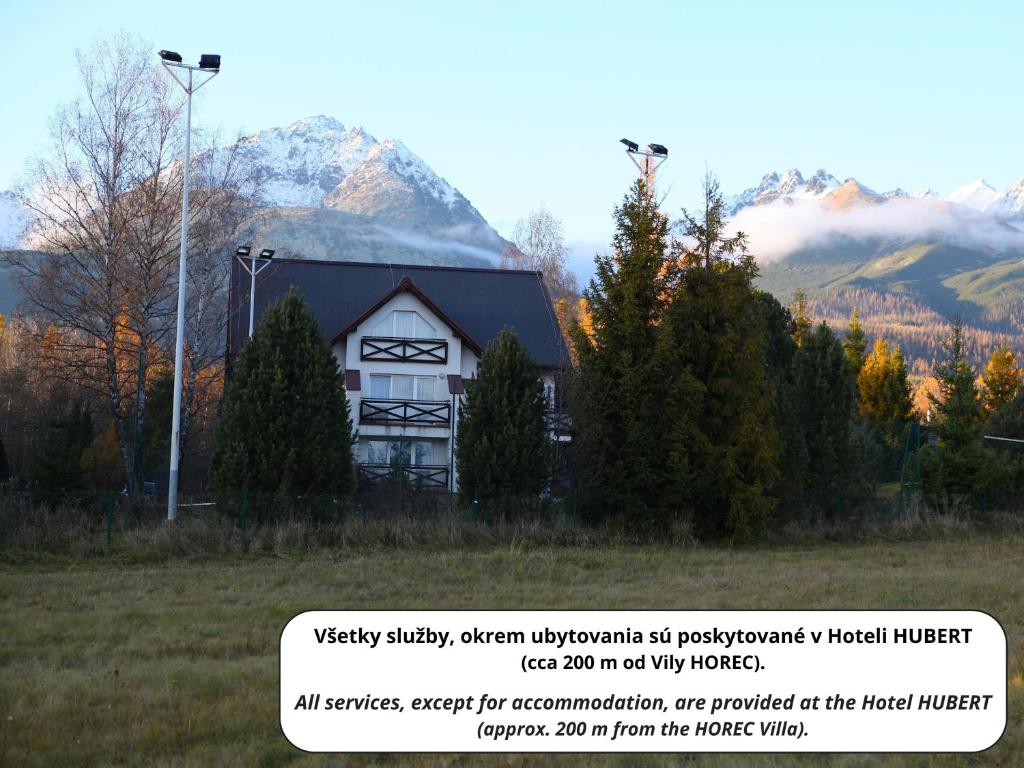 ein weißes Haus mit einem Berg im Hintergrund in der Unterkunft Vila Horec - depandance hotela Hubert Vital Resort in Vysoké Tatry