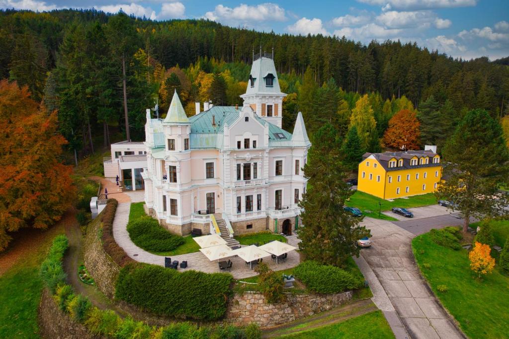 uma vista aérea de uma grande casa branca com uma torre em Hotel Château Cihelny em Karlovy Vary