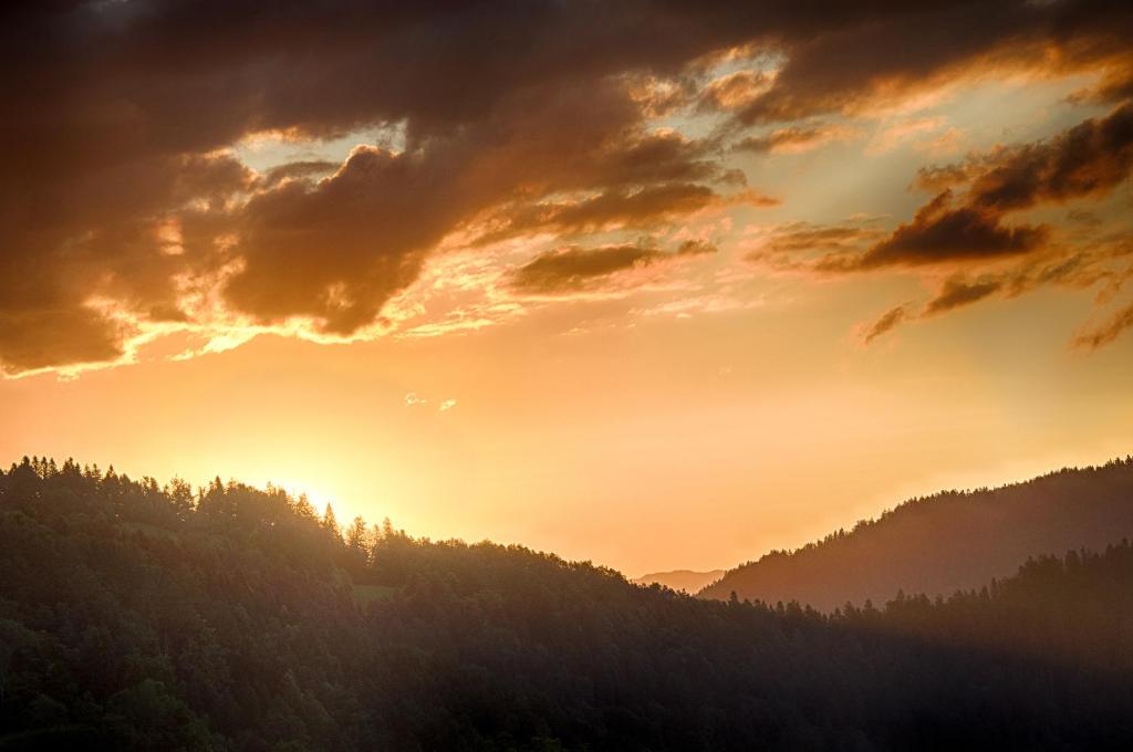 a sunset in the mountains with trees at Gostilna Pension Blegoš in Poljane nad Škofjo Loko