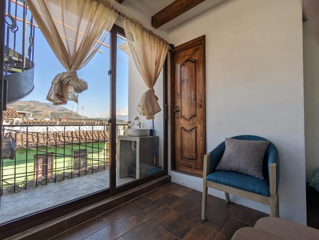 Cette chambre dispose d'une chaise et d'une grande fenêtre. dans l'établissement Vista Volcan, à Antigua Guatemala