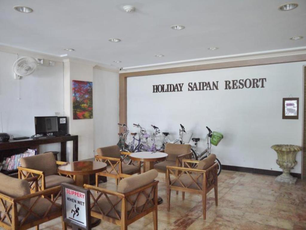 a waiting room with tables and chairs and a large screen at Holiday Saipan Hotel in Saipan