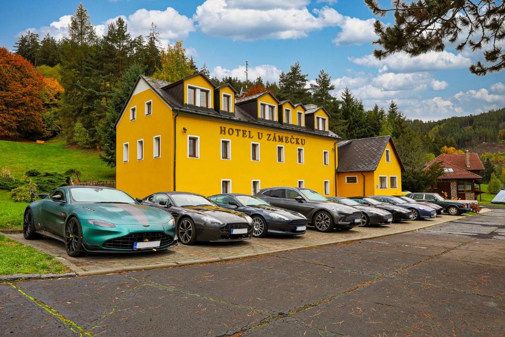 eine Reihe von Autos, die vor einem gelben Gebäude geparkt sind in der Unterkunft Hotel U Zámečku Cihelny in Karlsbad