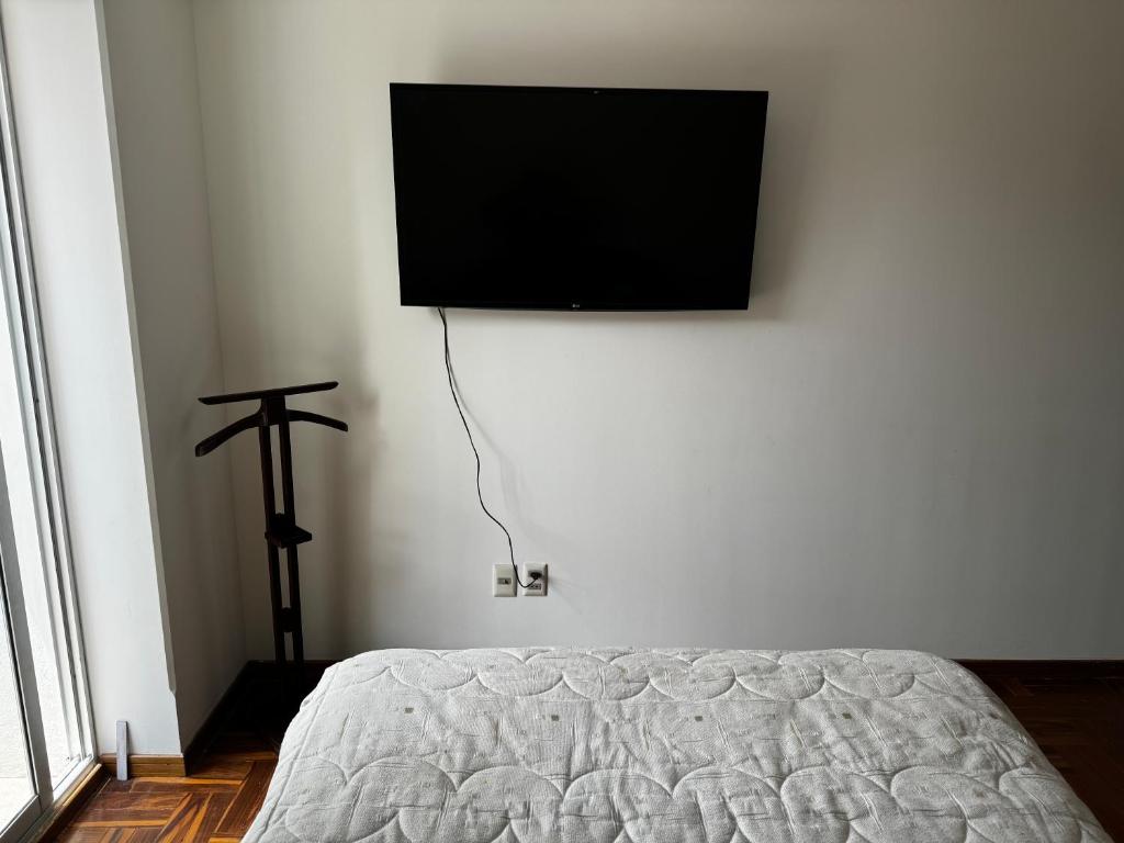 um quarto com uma cama e uma televisão de ecrã plano na parede em Smart Room em La Paz