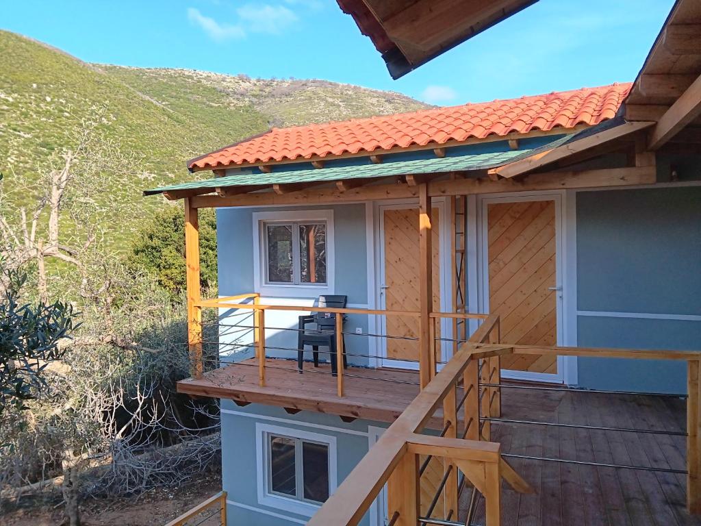 a house with a deck with a table on it at Tolis Rooms in Himare