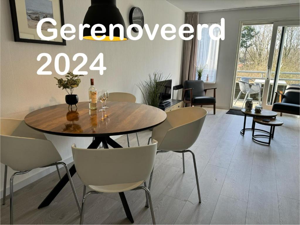 een eetkamer met een houten tafel en stoelen bij Appartement, Amelander Kaap 121 in Hollum