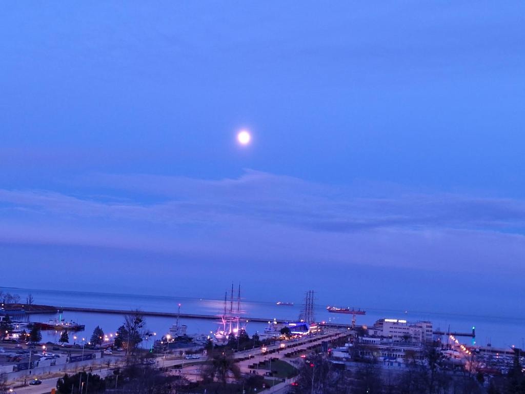 la luna piena sopra una città di notte di Apartament Skwer Kościuszki a Gdynia