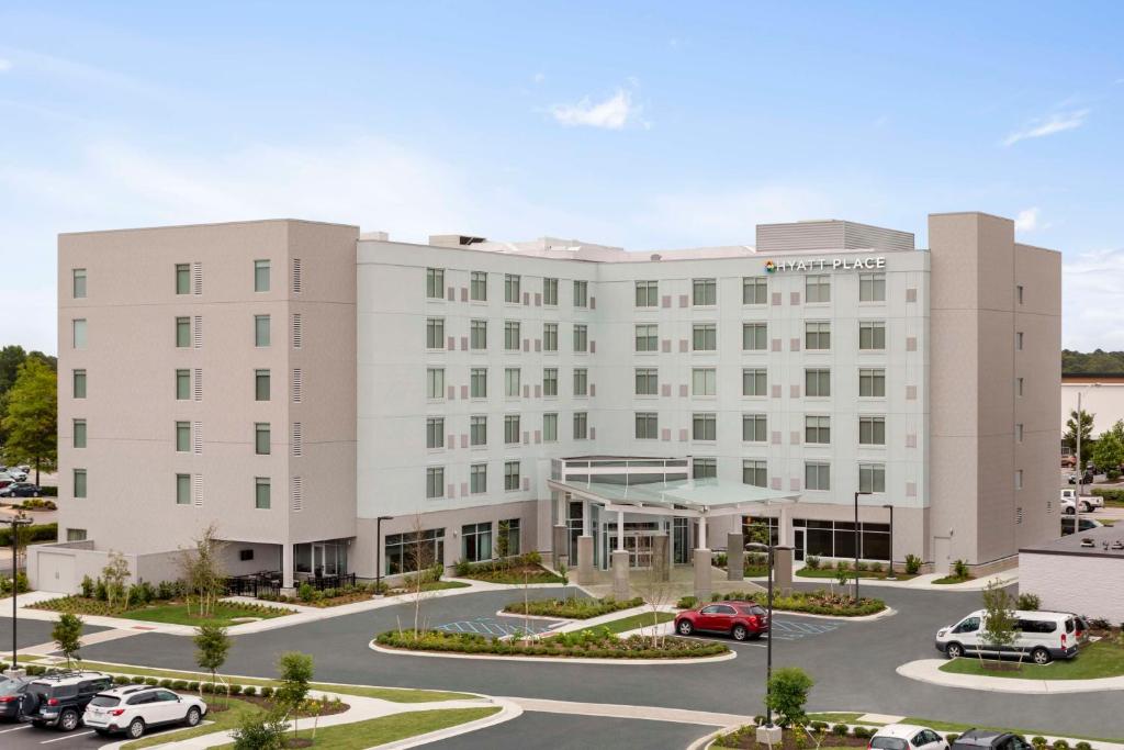 弗吉尼亚海滩Hyatt Place Virginia Beach Town Center的一座白色的大建筑,汽车停在停车场