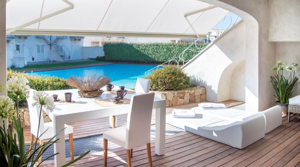 une terrasse avec une table et des chaises ainsi qu'une piscine dans l'établissement La Sciumara Resort Palau, à Palau