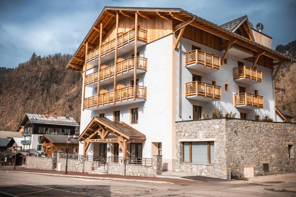 - un grand bâtiment blanc avec un balcon en bois dans l'établissement Hôtel de la Roche, à Beaufort