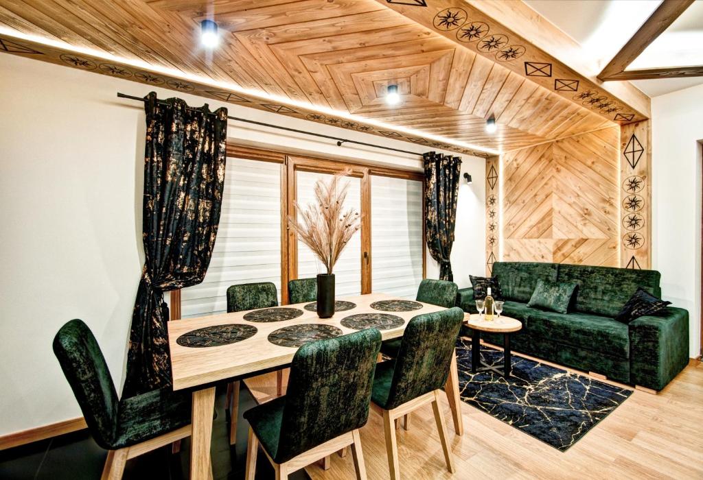 uma sala de jantar com uma mesa e cadeiras verdes em Domki pod Grapą JAKUZZI & DELUXE & Willa pod Grapą em Poronin