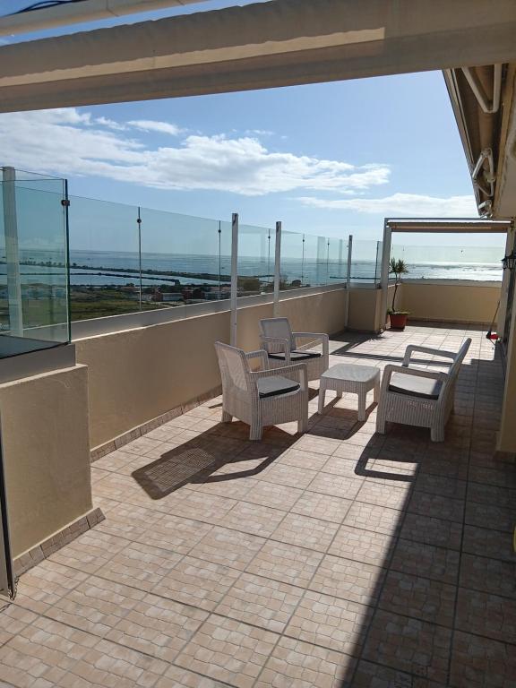 uma varanda com cadeiras e mesas e vista para o oceano em 7stars Apartment em Faro