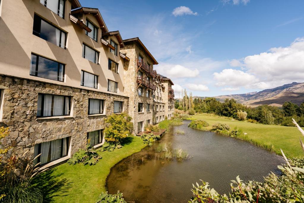 an apartment building with a river in front of it at Loi Suites Chapelco Hotel in San Martín de los Andes