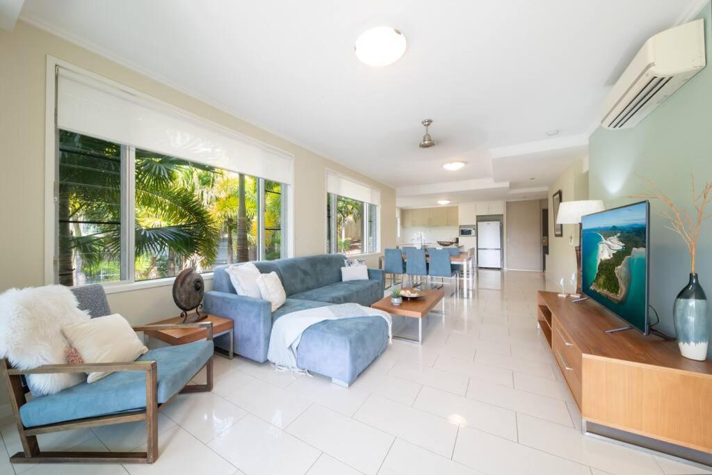 ein Wohnzimmer mit einem blauen Sofa und einem Tisch in der Unterkunft Whitsundays Ocean & Rainforest views Airlie Beach in Airlie Beach