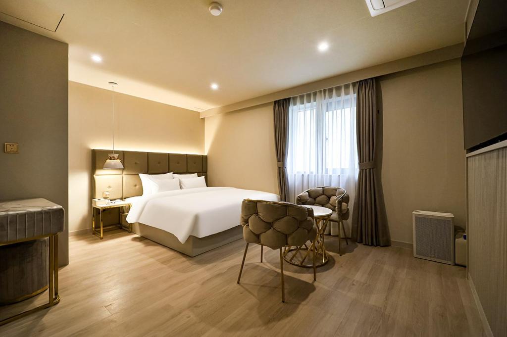 a hotel room with a bed and a table and chairs at Denbasta Hotel Daeyeon in Busan