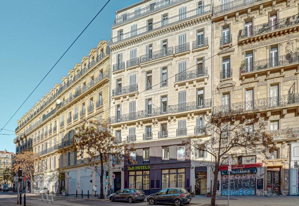 马赛B&B HOTEL Marseille Centre Vieux Port的一座大型建筑,前面有汽车停放