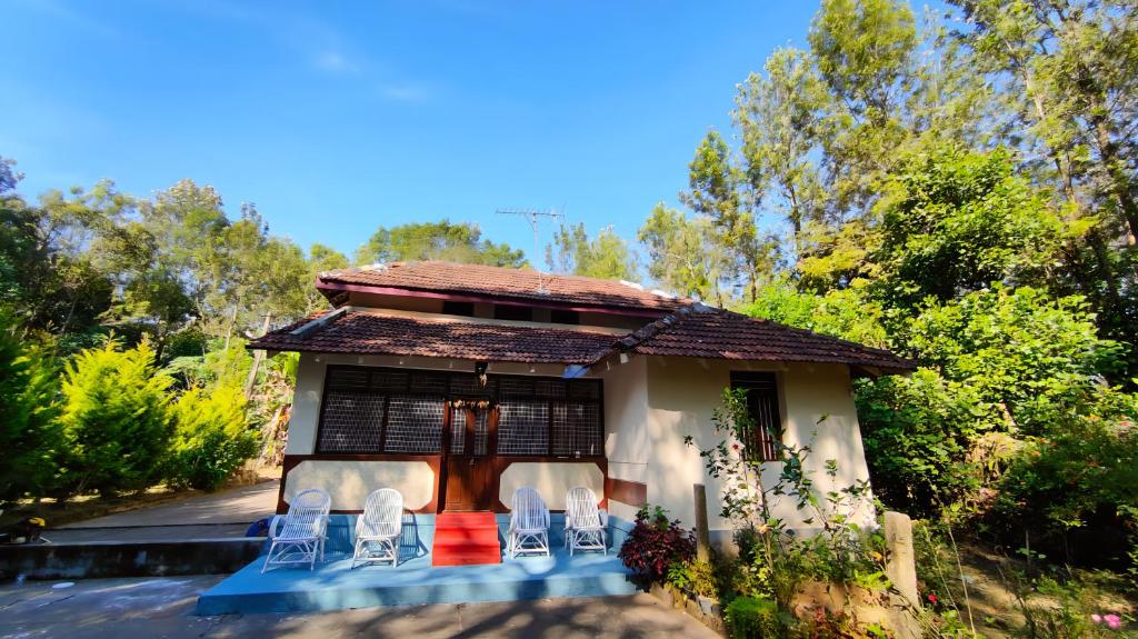 uma pequena casa com cadeiras em frente em Heritage Homestay em Chikmagalūr