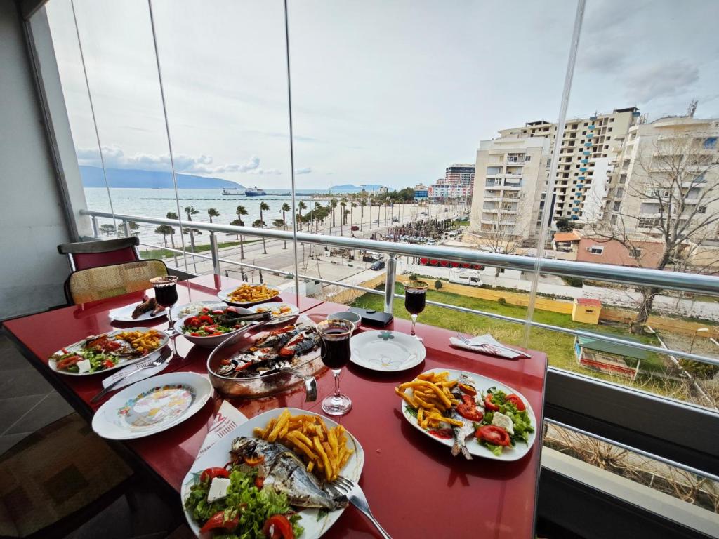 stół z talerzami jedzenia i widokiem na ocean w obiekcie Vasil Gjika Apartment we Wlorze