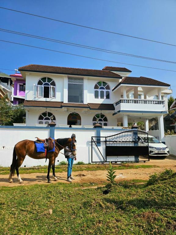 un homme tenant un cheval devant une maison dans l'établissement Hestia Chalet 3BHK Villa, à Ooty