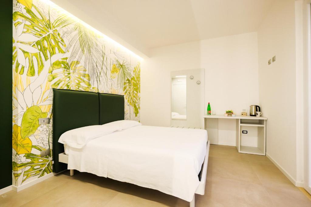 um quarto com uma cama branca e um papel de parede tropical em Casa dei Venti - Guest House em Terracina