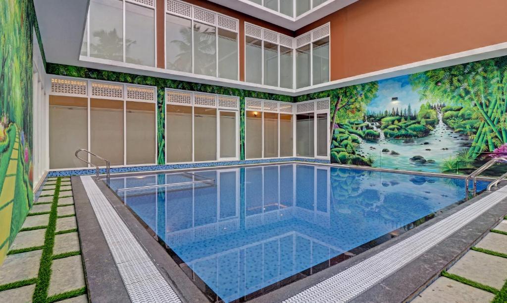 - une piscine avec une fresque murale sur le côté d'un bâtiment dans l'établissement Treebo Golden Terminal, Kochi Airport, à Cochin