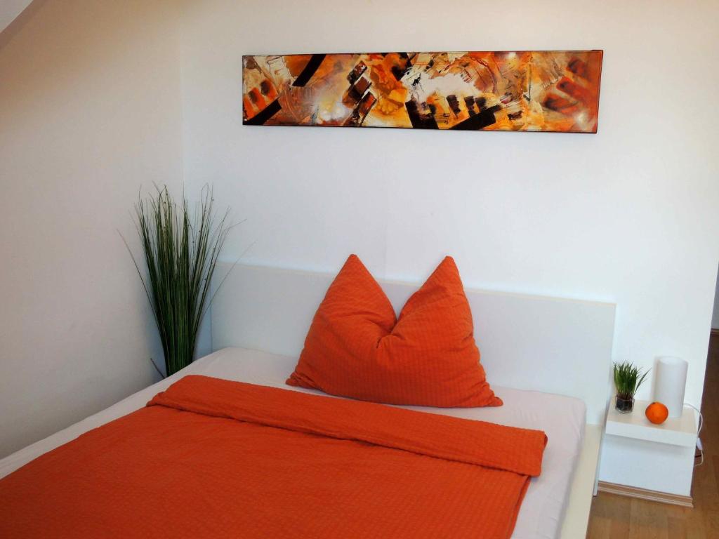 a bedroom with orange pillows and a painting on the wall at Appartement Föhrenvilla in Mödling