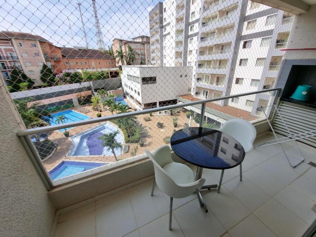 einen Balkon mit einem Tisch, Stühlen und einem Pool in der Unterkunft Flat Hotel Veredas Rio Quente Hot Park apto 216, 323 e 522 in Rio Quente