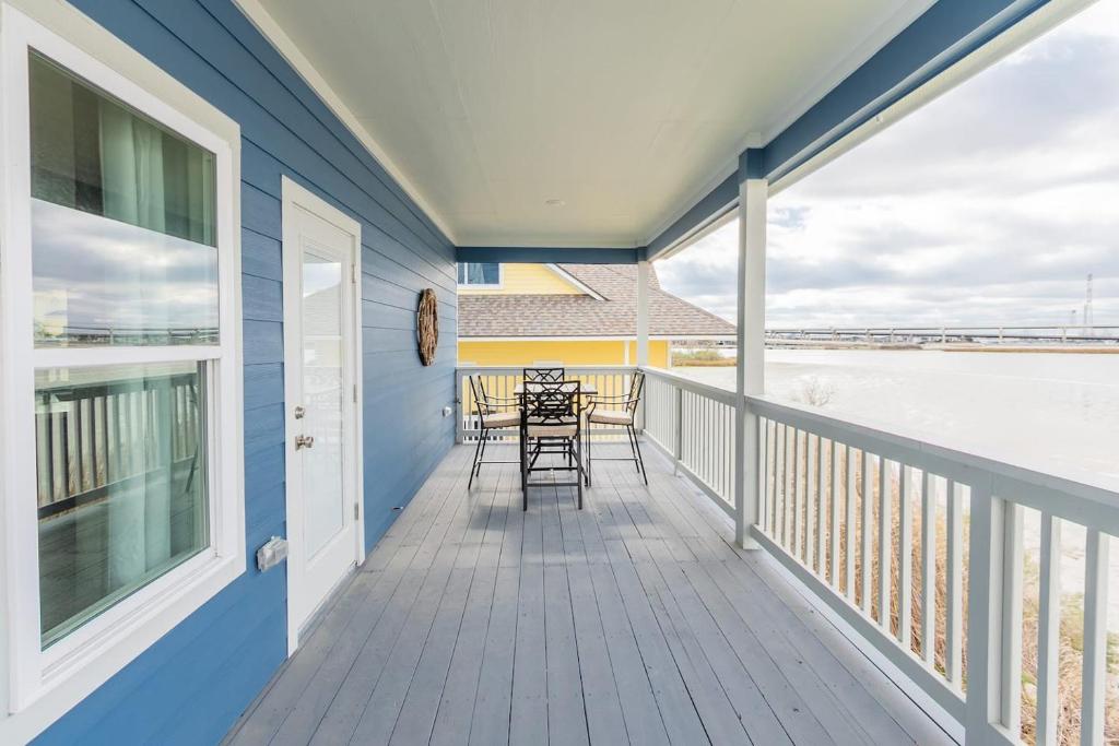 een balkon met tafels en stoelen in een blauw huis bij Water Front 3 25 Bath Kingbed Kemah Seabrook in Seabrook