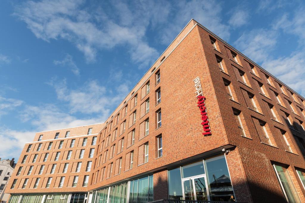 - un bâtiment en briques avec un panneau rouge dans l'établissement IntercityHotel Lübeck, à Lübeck