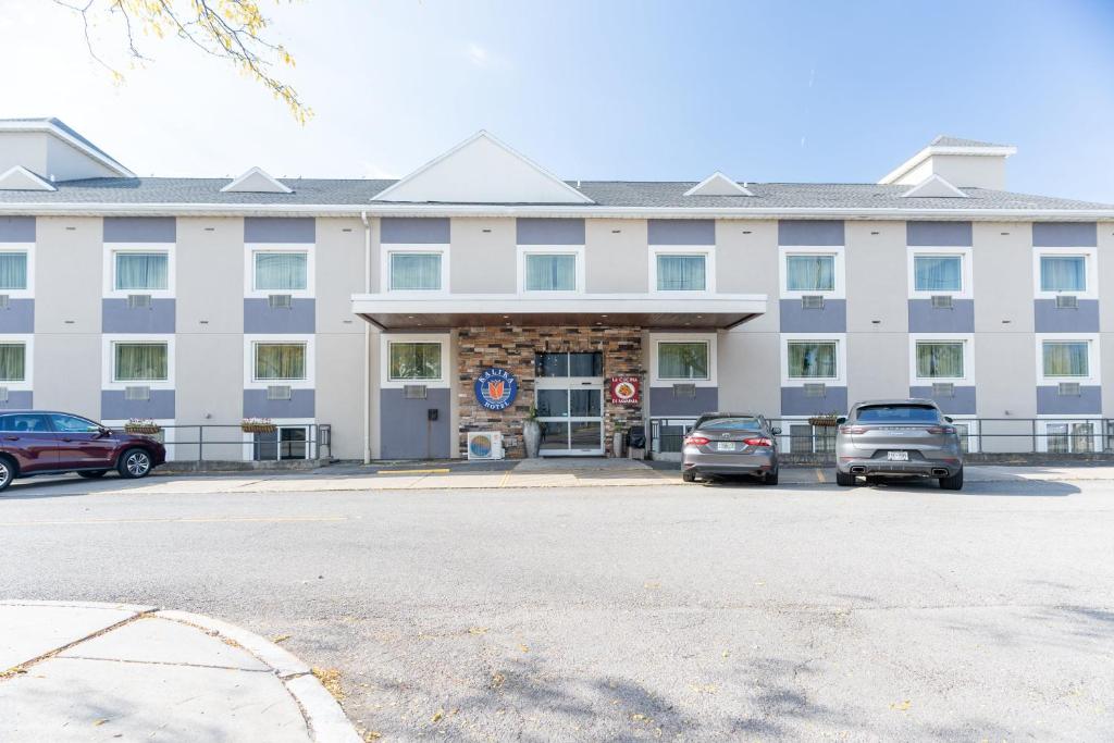 un grande edificio bianco con auto parcheggiate in un parcheggio di Kalika Hotel a Niagara Falls