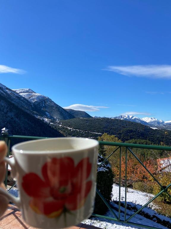 een kopje koffie op een balkon met uitzicht bij Villa Nano Kalavryta Βίλα στο βουνό με τζάκι κοντά στο χιονοδρομικό in Kalavrita