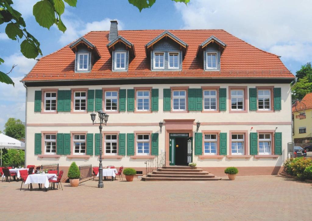 uma casa grande com telhado vermelho e persianas verdes em Hotel Restaurant Ölmühle em Landstuhl