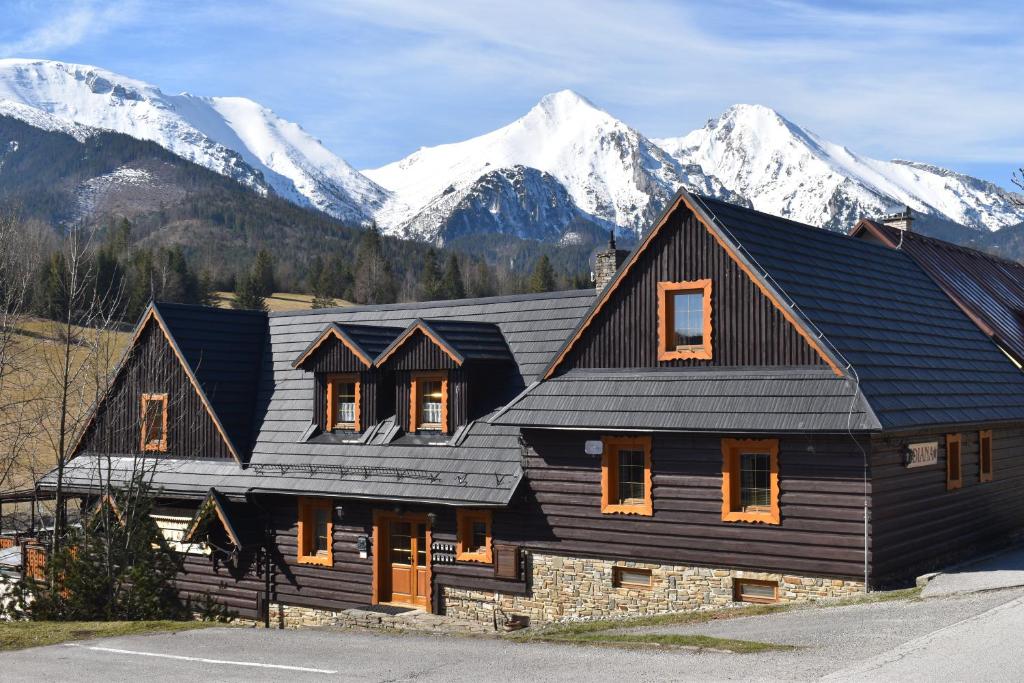 une grande maison en bois avec des montagnes en arrière-plan dans l'établissement Drevenica Diana, à Ždiar