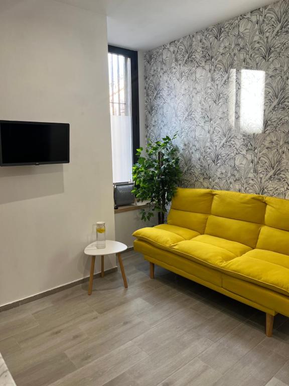 ein gelbes Sofa im Wohnzimmer mit einem TV in der Unterkunft Apartamento Chic Centro in Dos Hermanas