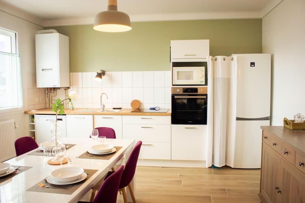 een keuken met een tafel en een witte koelkast bij « Le Randonneur » in Albertville