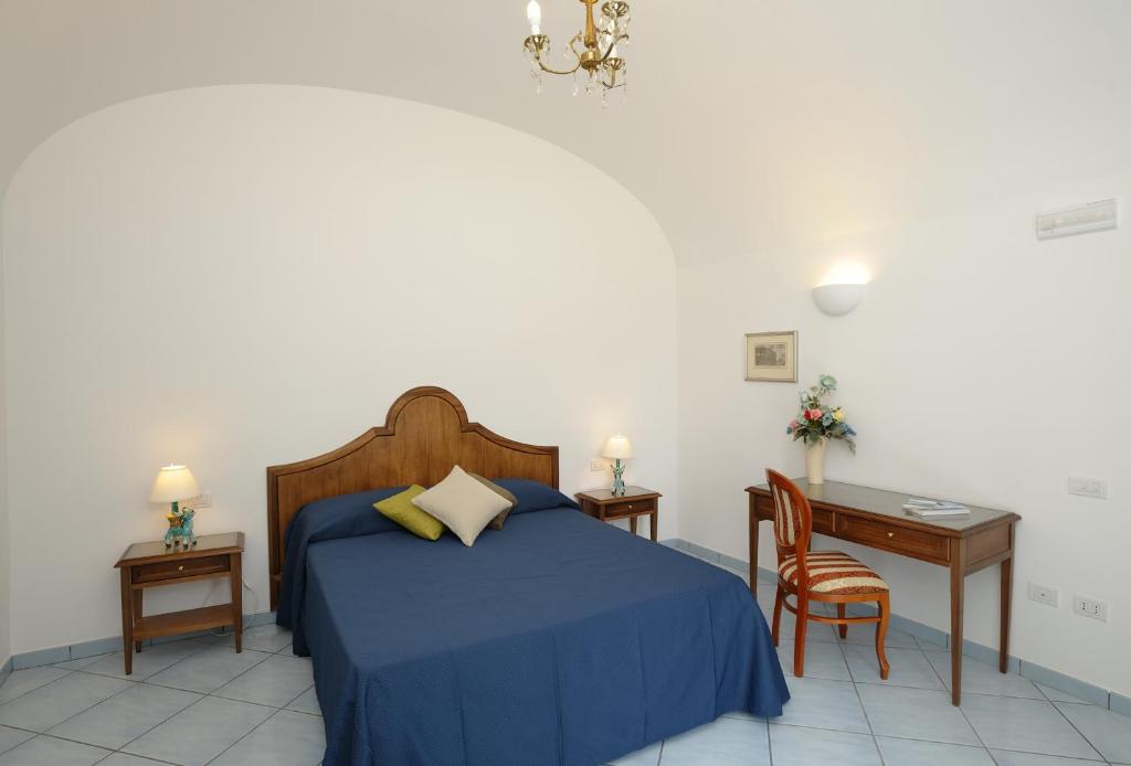 een slaapkamer met een blauw bed, een bureau en een stoel bij Il Ducato Di Ravello in Ravello