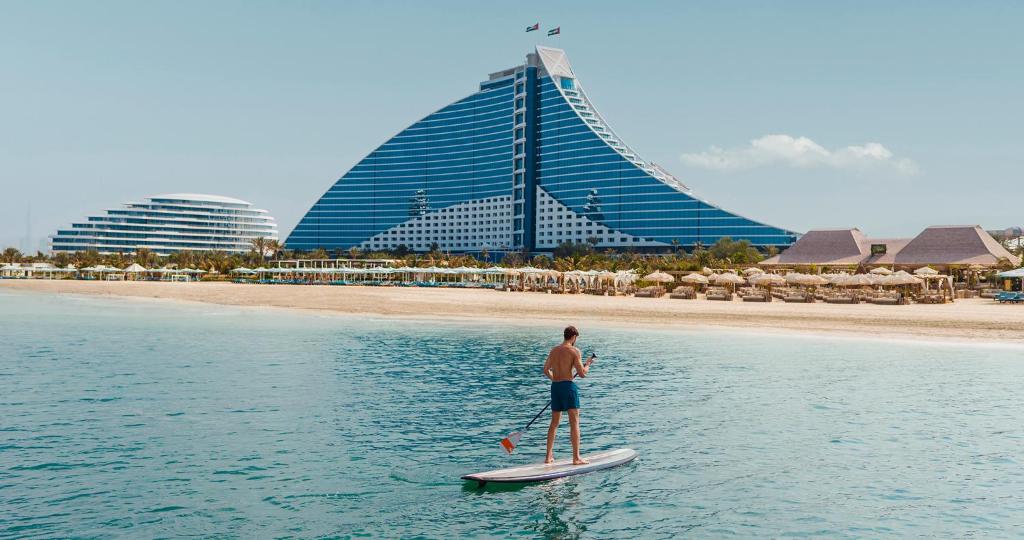 Ein Mann steht auf einem Paddelbrett im Wasser in der Unterkunft Jumeirah Beach Hotel Dubai in Dubai