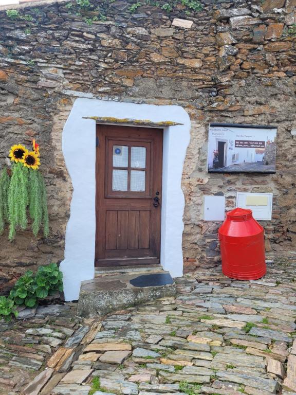 una puerta en un edificio de piedra con un cubo rojo en Estúdio Tia Anica, en Reguengos de Monsaraz