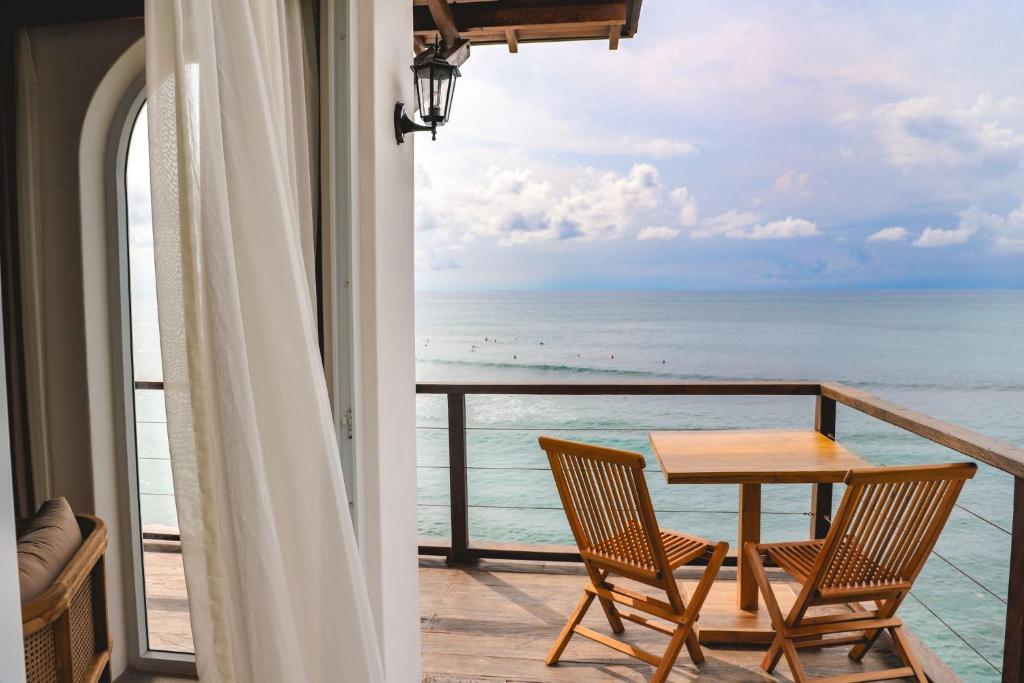 d'un balcon avec une table et des chaises donnant sur l'océan. dans l'établissement Sabbia by Nyoman and Nyoman, à Uluwatu