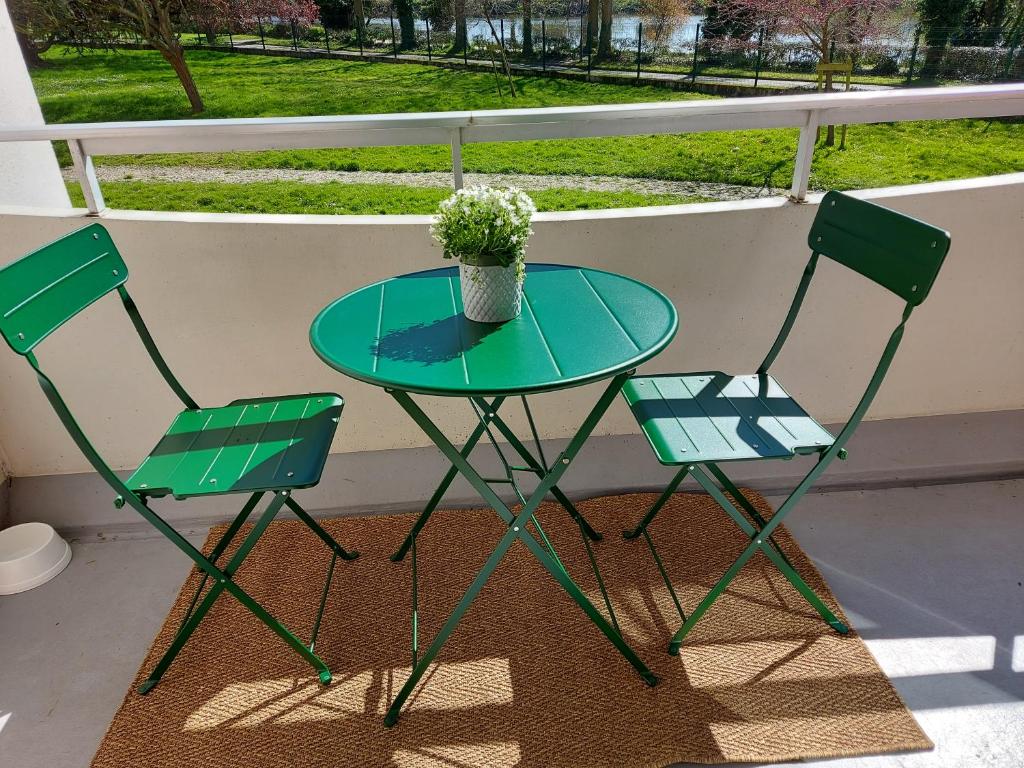 2 chaises et une table avec un vase de fleurs sur le balcon dans l'établissement Appartement Rennes stade parking gratuit, à Rennes