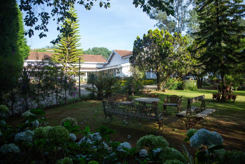 un jardín con un banco y una mesa en el patio en Marlihill Bungalow - a CGH Earth SAHA Experience, en Ooty