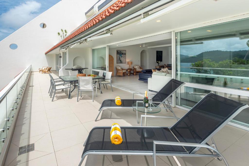 einen Balkon mit Stühlen und Tischen auf einem Haus in der Unterkunft Bella Vista East 4 Oceanview, Golf Buggy, Valet Service & Shared Pool in Hamilton Island