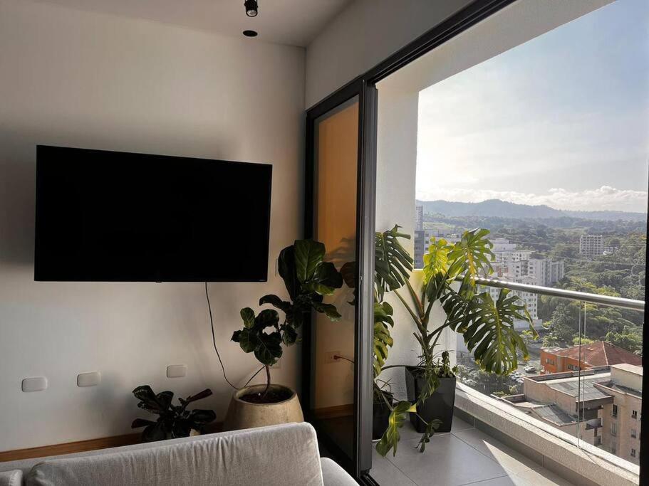 a living room with a flat screen tv and plants at Lujoso apartamento central, nuevo y cómodo in Pereira