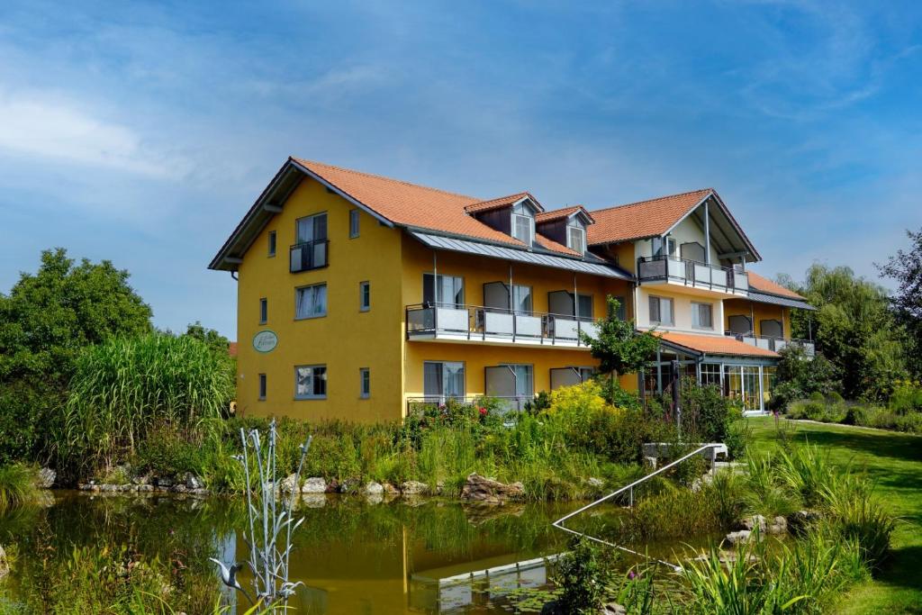 un grand bâtiment jaune avec un étang devant lui dans l'établissement Landhotel Larenzen, à Kirchham