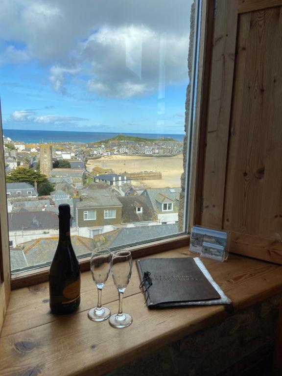 okno z butelką wina i dwoma kieliszkami wina w obiekcie HUER'S WATCH a beautifully presented PRIVATE APARTMENT with far reaching VIEWS Over ST IVES HARBOUR and BAY and FREE ONSITE PARKING for LARGER GROUPS book along with our Connecting TWO SISTER APARTMENTS w St Ives