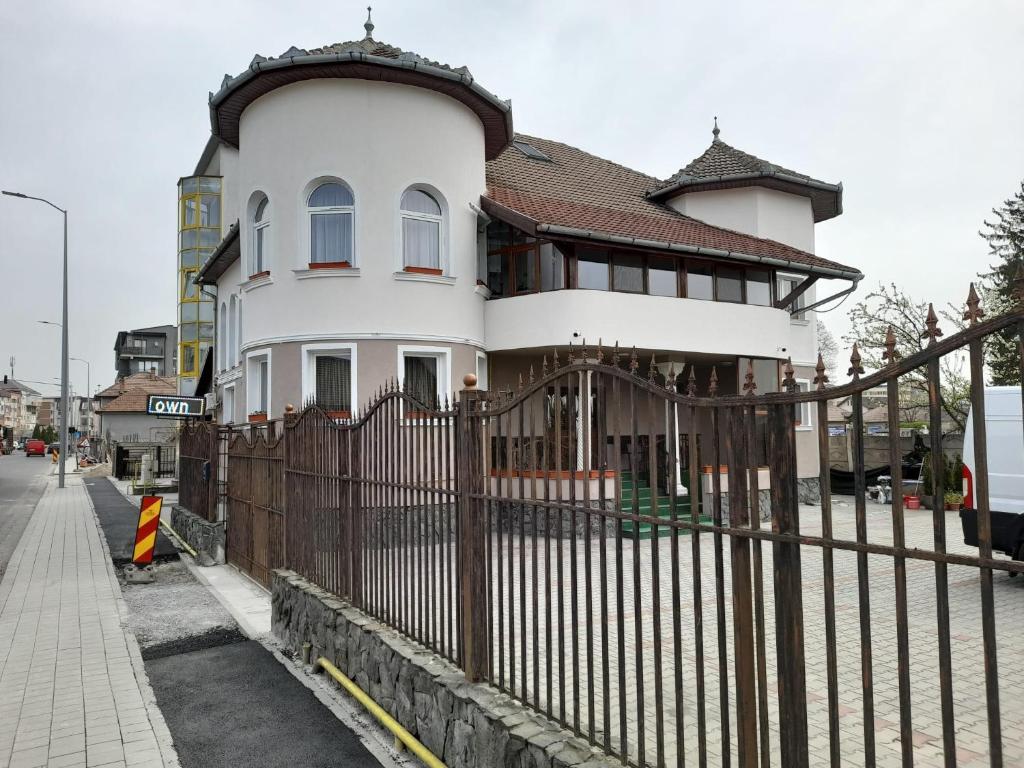 a white house with a fence in front of it at Pensiunea Crown Royal in Alba Iulia